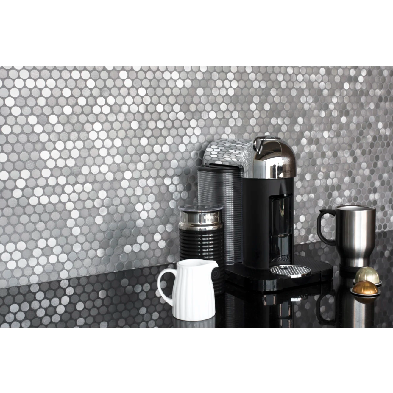 Polished black granite countertop with coffee maker and silver mug placed on top, against Penny round tile in the color Iron.