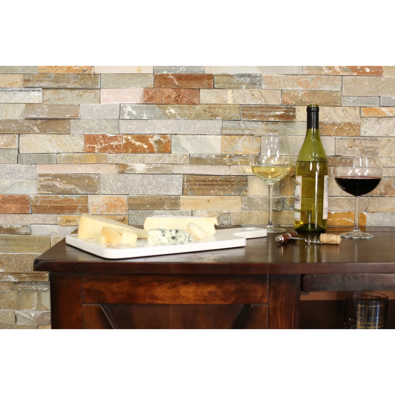 Split-face ledger wall application with a cabinet in front with an open, green, wine bottle, two wine glasses, and a plate of cheese.