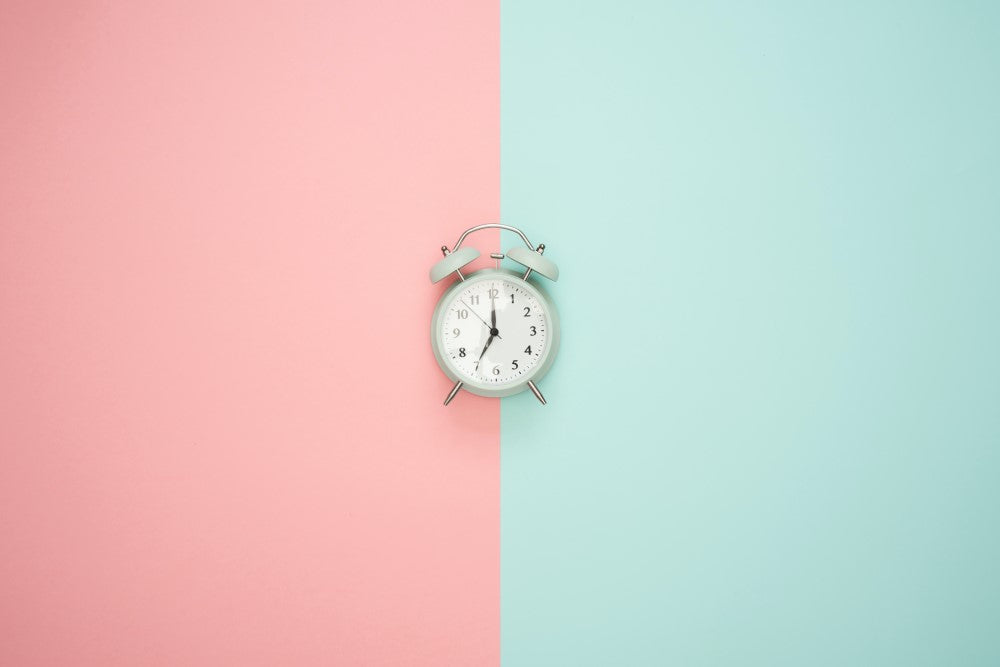 White alarm clock and pink and turquoise background