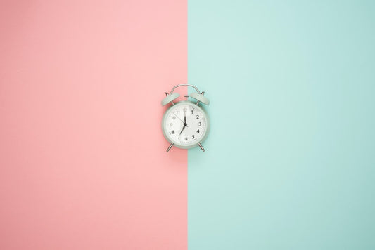White alarm clock and pink and turquoise background