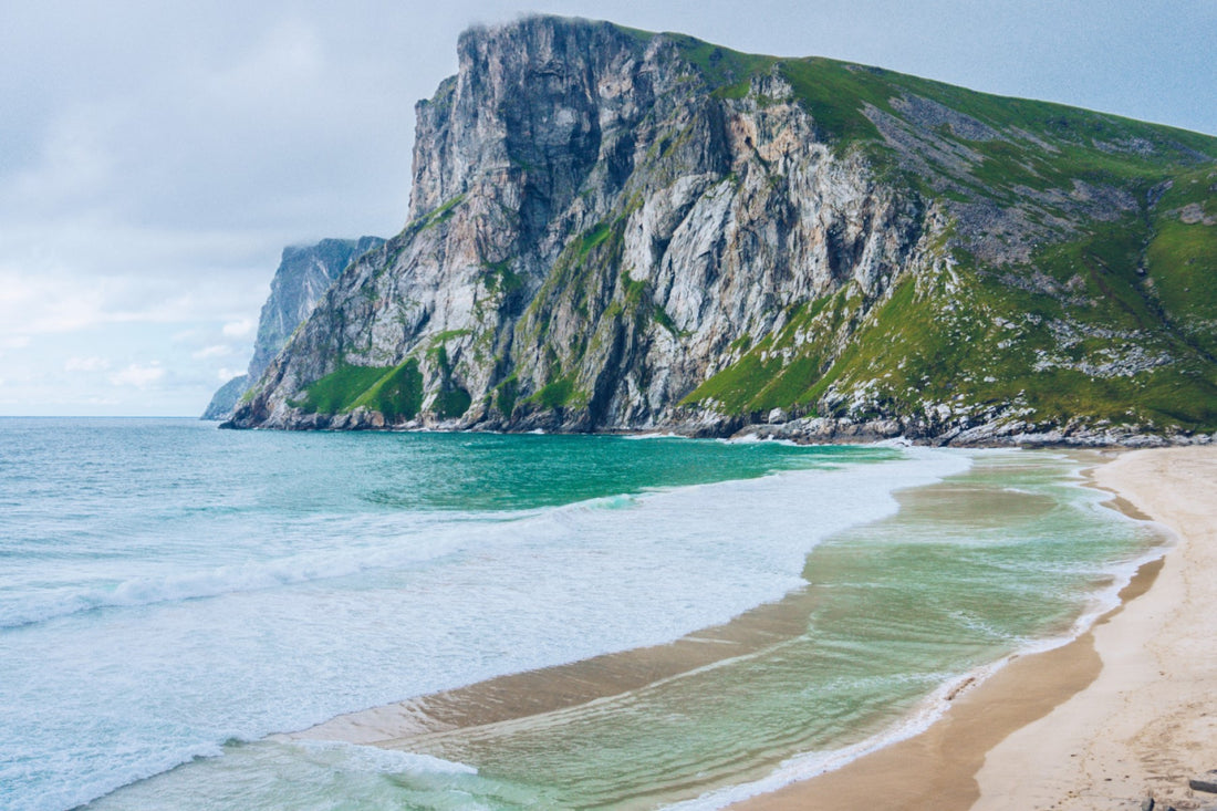 Waves breaking on beach with rocky cliffside