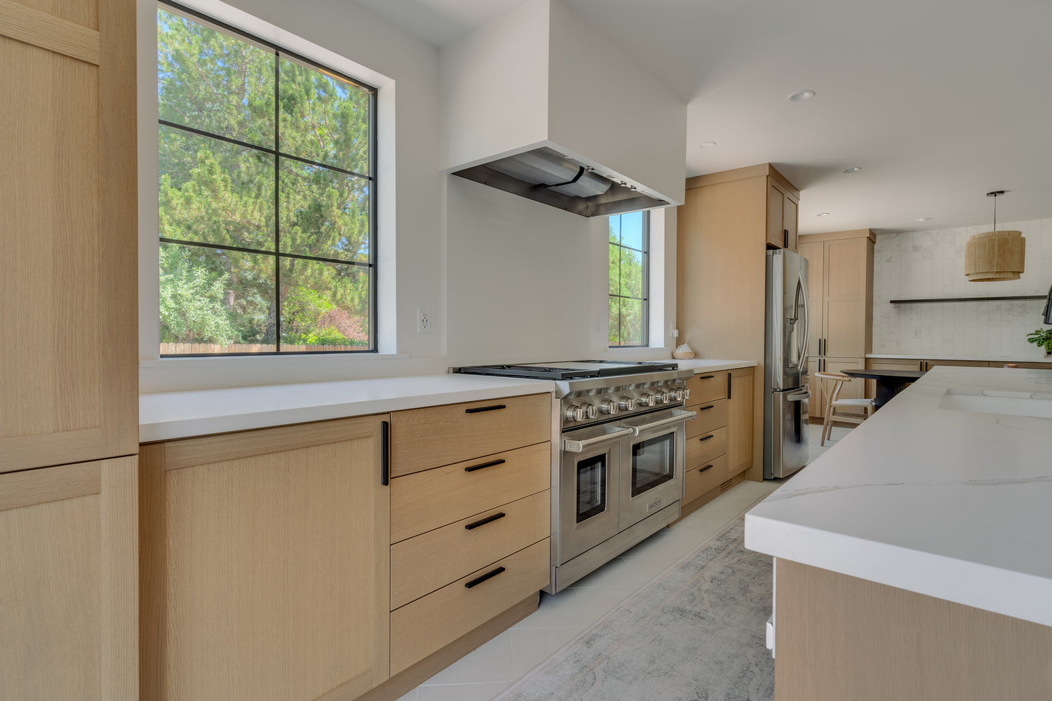 Modern kitchen with wooden cabinets, stainless steel appliances, and a large window.