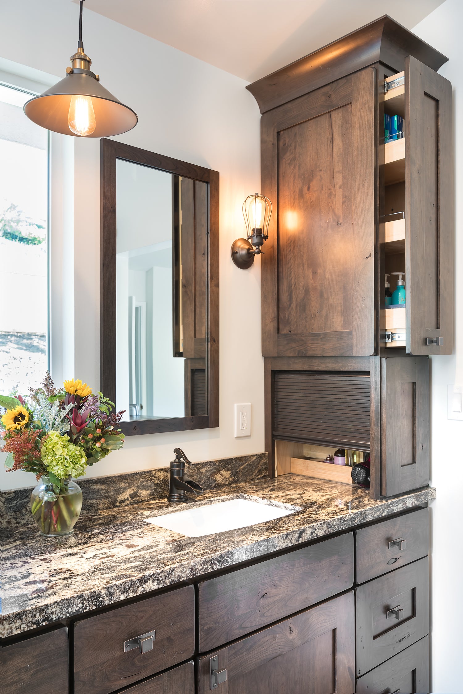Bathroom with wooden vanity, granite countertop, and open cabinet with appliance garage and pull-out storage