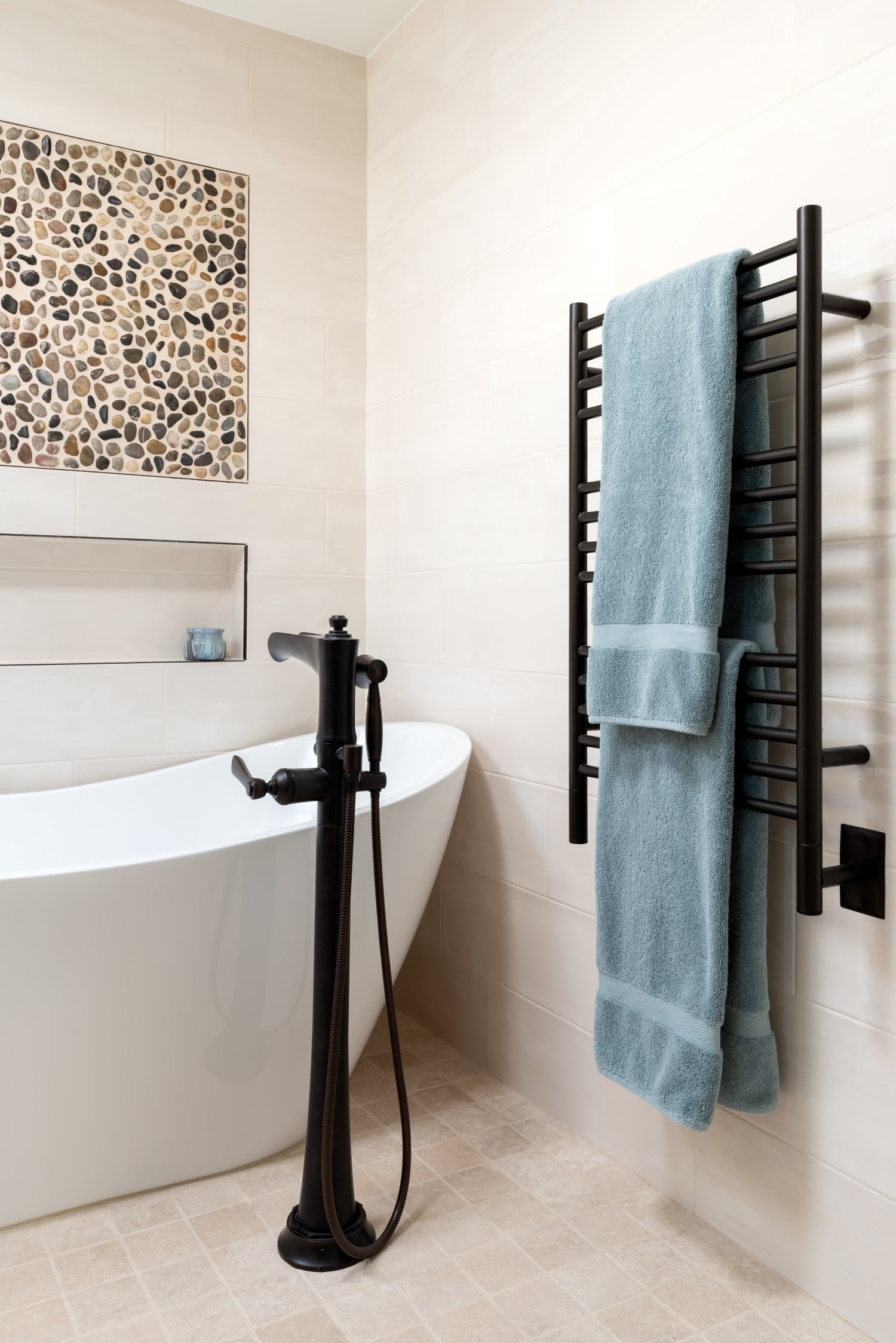 Bathroom with a freestanding bathtub, black faucet, and towel rack with a blue towel.