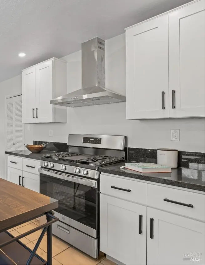 Modern kitchen with white cabinets, stainless steel appliances, and a wooden dining table