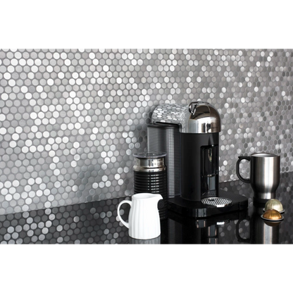 Polished black granite countertop with coffee maker and silver mug placed on top, against Penny round tile in the color Iron. 