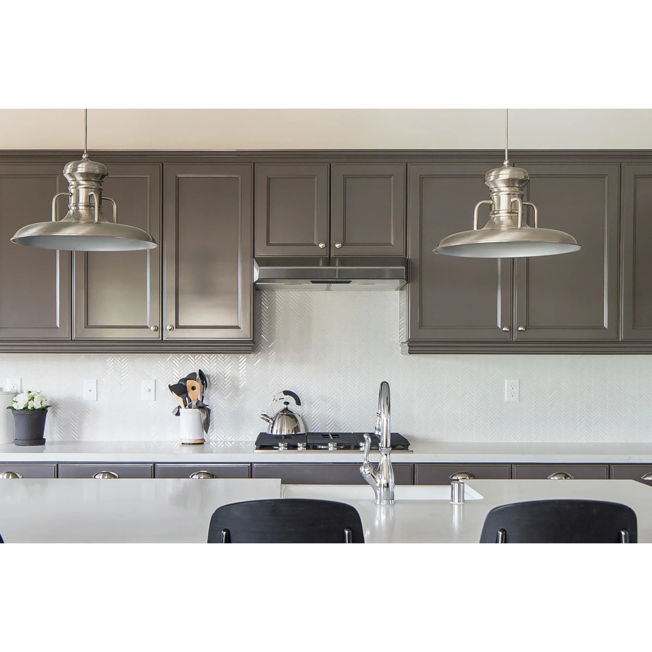 White and brown kitchen with Herringbone tile in the color White as a backsplash.