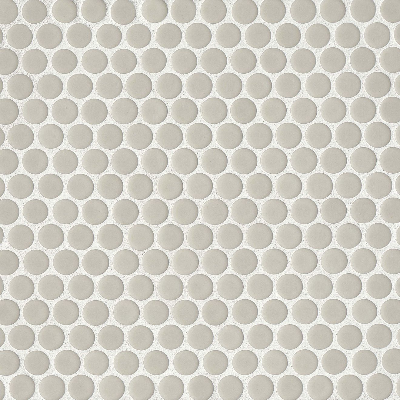 Off white penny shaped mosaic tile on a beige background.