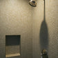 Beige penny round tile lining shower wall.