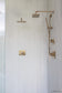 White matte field tile laid vertically on shower wall with gold plumbing and hardware.